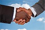 This is an image of two business hands performing a handshake, with a cloud background.