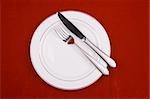 Place setting of a dinning set in red background.