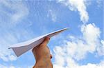 Hand launching paper plane into blue sky