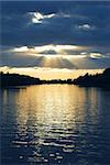 Rays of sun shining through the clouds and sunset over water