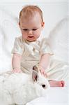 cute little girl dressed like fairy with fluffy wings plays with white rabbit