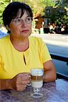 Mature woman in outdoor cafe with coffee looking sad