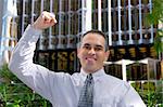 Triumphant businessman in the city raising an arm in victory