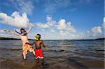 Two young boys playing with snorkel gear in the water - one African American and one Caucasian. John Pennecamp Park, Florida Keys.