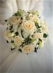 Wedding bouquet from beige roses on a background of a wedding dress