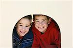 Two boys playing looking through a tunnel