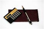 A check book, calculator and a pen against a white background