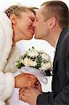 newlywed bride and groom kissing and holding flowers