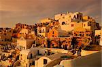 Image shows the traditional village of Oia, on the Greek island of Santorini with hundreds of tourists waiting for one of its famous sunsets