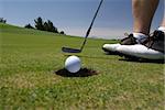 Close up image detail of a golfer putting and the ball dropping into cup