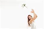 Portrait of Caucasian bride tossing bouquet behind her.