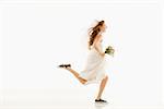 Caucasian bride running and holding bouquet.