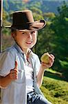 Friendly mountain boy sitting on the balcony in the afternoon eating fresh fruit and giving the thumbs up