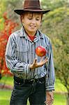 A boy standing in pristine countryside is throwing up a fresh organic red apple. eg:  green living, healthy lifestyle, organic produce, nature's best,  Special Note: motion in apple and hand, 400iso