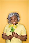 African American female mature adult holding flowers looking at viewer smiling.