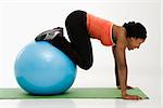 Profile of African American woman working out using an exercise ball.