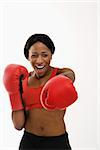 African American young adult woman wearing boxing goves throwing playful punch at viewer.