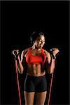 Smiling African American young adult woman exercising with resistance tube.