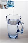 glass and bottle with water on white background