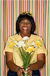 African-American  mid-adult woman laughing holding flowers.