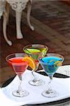 three colorful alcoholic drinks are prepared and served