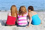 Portrait of three teenage girls sitting on a sandy beach