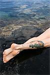 Legs of tattooed Caucasian woman lying in tidal pool in Maui, Hawaii, USA.