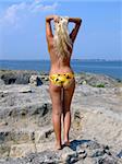 The sexual girl standing on a stone and looks at the sea