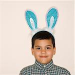 Portrait of Hispanic boy wearing bunny ears looking at viewer.