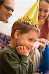 Caucasian boy at  birthday party looking to the side and smiling.