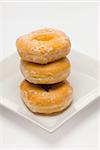 Three glazed donuts on a white plate