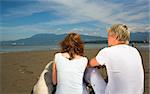 young couple on the beach with dog in vancouver - shot from behing