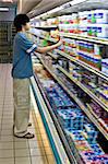 Young man shopping in a supermarket, fridge displays