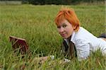 young woman with red notebook on grass