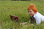 young woman with red notebook on grass
