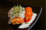 fresh salmon slice on white platter with salad and prawns served with yogurt cream