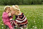 Woman and baby girl having fun on the spring meadow full of daisies