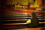 A back view of praying sister inside church