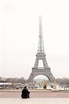 A person sitting, looking at the Eiffel Tower in Paris, France.  Copy space.