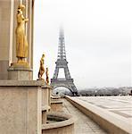 A golden statue in the foreground with the Eiffel Tower in Paris, France.  Copy space.