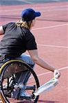 A wheelchair tennis player during a tennis championship match, returning a shot. Motion blur on her racket.