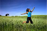Young active woman jumping on a green field
