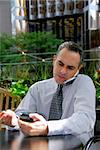 Portrait of a busy businessman in the city using pda and cell phone