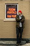 Man Leaning Against Building with Neon Sign