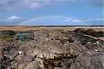 a rocky beach on a warm wet day with a calm sea and a rainbow after a shower an ideal place to have a walk in ireland