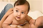 Mom lying down on bed and infant baby lies on her stomach