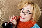 Crazy woman with wild eyes drinking wine through a straw