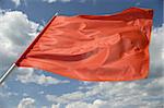 Red flag on a background of the dark blue sky with clouds.