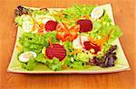 Salad with lettuce, tomatoes, carrot, corn, egg and beet on wooden background. Shallow depth of field