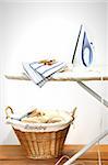 Ironing board with laundry against white background